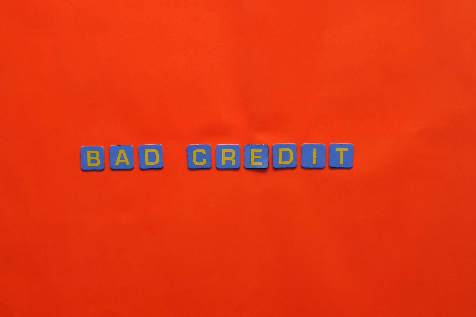 Blue letter blocks spelling 'Bad Credit' on an orange background.